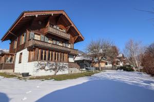 ein Haus im Schnee mit einer Reflexion im Vordergrund in der Unterkunft Valrose in Chateau-d'Oex