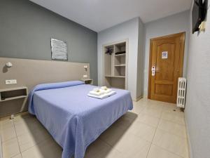 1 dormitorio con 1 cama con manta azul en Hostal Soto en La Virgen del Camino