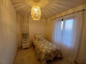 a bedroom with a bed and a chandelier and a window at L'Olivier in Mormoiron