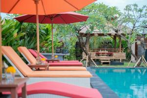 een zwembad met stoelen en parasols naast een zwembad bij Villa Felise in Sanur