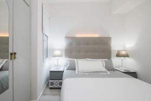 a white bedroom with a large bed and two lamps at Near FCB STADIUM. One car free parking. in Barcelona