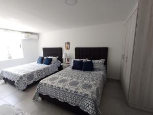 2 Betten in einem weißen Zimmer mit blauen Kissen in der Unterkunft PARK 83 Apartaestudios in Cali