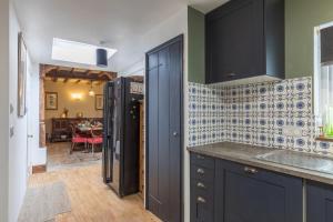a kitchen with black cabinets and blue tiles on the wall at Wisteria House, 6 beds Central Uckfield East Sussex in Uckfield