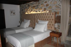 2 Betten in einem Schlafzimmer mit einer Steinmauer in der Unterkunft Casal da Batoca Nature House in Fafe