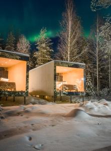 a building in the snow with the northern lights in the sky at Kuuru Lakeside in Salla