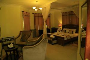 a bedroom with a bed and two chairs in it at Royal Victoria House in Kampala