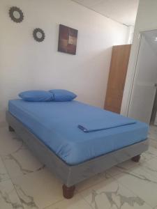 1 cama con sábanas azules en una habitación con pared en DEPARTAMENTO-MANTA, Playa Murciélago, en Manta