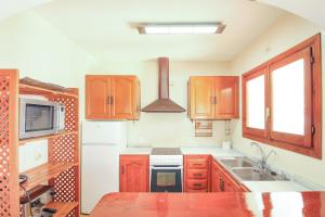 una cocina con armarios de madera y fregadero en Villa con piscina privada - Benicolada en Calpe