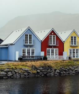 une rangée de maisons devant une masse d'eau dans l'établissement New Boat House, à Leirvík