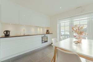 - une cuisine blanche avec une table et des chaises dans l'établissement New Boat House, à Leirvík