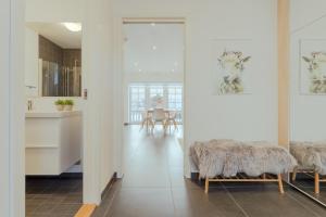 una sala de estar con paredes blancas y una cocina con mesas. en New Boat House, en Leirvík