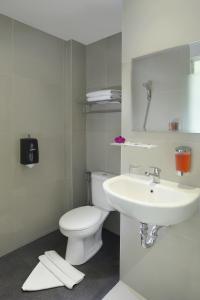 a white bathroom with a toilet and a sink at Zizz Convention Hotel in Denpasar