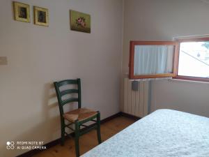 ein Schlafzimmer mit einem Stuhl, einem Bett und einem Fenster in der Unterkunft Appartamento Bucaneve in Ovindoli