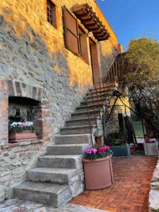 a stone building with stairs and a window and flowers at Atelier Fuori Città in Perugia