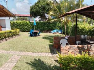 - un jardin avec une table, des chaises et un parasol dans l'établissement Casa de campo San Fernando, à Villeta