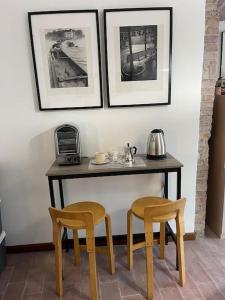 stół z dwoma krzesłami i dwa zdjęcia na ścianie w obiekcie Atelier Fuori Città w mieście Perugia