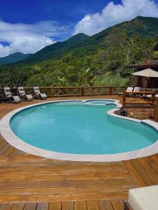 a swimming pool on a deck with mountains in the background at Mooi Guest House in Ilhabela