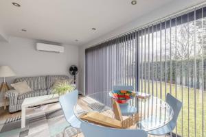 a living room with a glass table and a large window at Cosy Home Near Sunningdale/Ascot/Wentworth Golf Club in Sunninghill