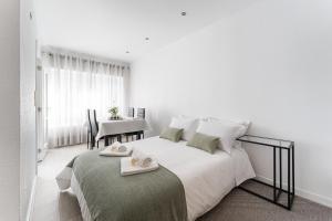 um quarto branco com uma cama com duas toalhas em Casa Trindade no Porto