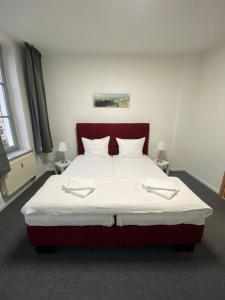 1 dormitorio con 1 cama grande con sábanas y almohadas blancas en Pension Villa Ostseetraum en Warnemünde