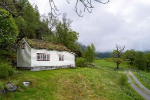 una pequeña casa blanca en un campo de hierba en Fossane gard, en Hjelmeland
