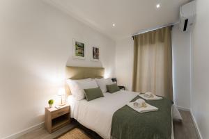 um quarto com uma grande cama branca com um cobertor verde em Casa Trindade no Porto
