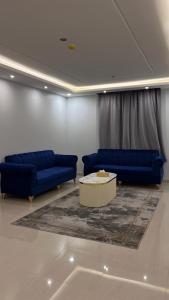 a living room with two blue couches and a table at شقق جوانة in Riyadh