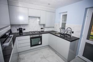 a white kitchen with white cabinets and black counter tops at la vida in casa in Thamesmead