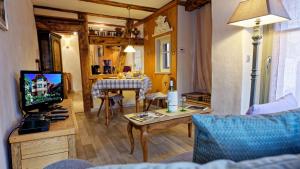a living room with a television and a table at Remparts de Riquewihr - Le Petit Loup in Riquewihr