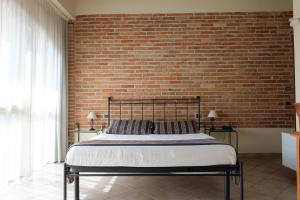 a bed in a room with a brick wall at Hotel Le Botti in Guarene