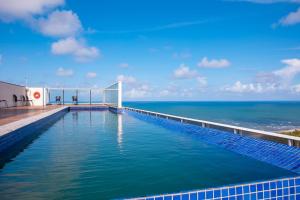 a swimming pool with the ocean in the background at Paiva Home Stay - Vista dos Sonhos in Recife