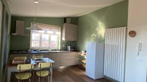 a kitchen with green walls and a white refrigerator at LuccaStay in Lucca