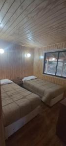 a room with two beds and a window at Cabañas El Maitén in Castro