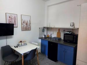 een kleine keuken met een witte tafel en blauwe kasten bij Studio 91 By IsrApart in Ramat Gan