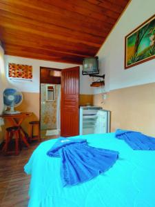 a bedroom with a blue bed with a tv on the wall at Quarto Maringá Minas in Bocaina de Minas