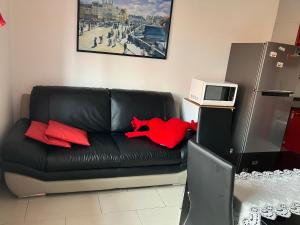 un sofá negro con almohadas rojas en la sala de estar. en Mechai Boatto Tumpat, en Marghera