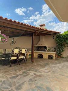 un patio con mesa, sillas y chimenea en Ερέτρια ~Ένας προορισμός μια ανάσα από την Αθήνα en Eretria