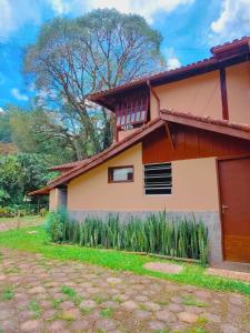 a house with a tree in the background at Quarto Maringá Minas in Bocaina de Minas