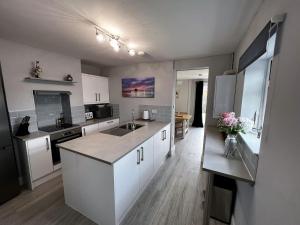 uma cozinha com armários brancos e uma bancada em Kema Cottage em East Cowes