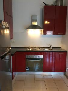 uma cozinha com armários vermelhos e um forno com placa de fogão em Mechai Boatto Tumpat em Marghera