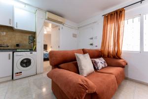 a living room with a brown couch in a kitchen at MalagaSuite City Center Torremolinos in Torremolinos