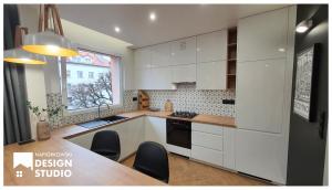 a kitchen with white cabinets and a table with chairs at APARTAMENT ODRODZENIA 14 in Szczytno