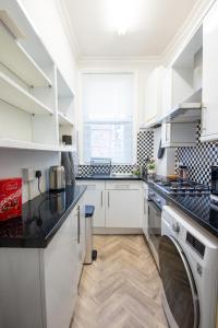 a kitchen with white cabinets and black counter tops at Modern Spacious Holiday Home 75 in London
