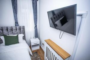 een slaapkamer met een bed en een flatscreen-tv aan de muur bij la vida in casa in Thamesmead