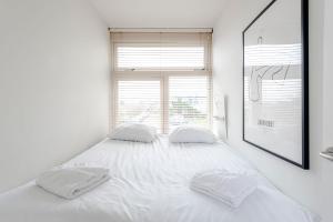 a white bedroom with a large bed with two pillows at De Schelp 85 in Zandvoort