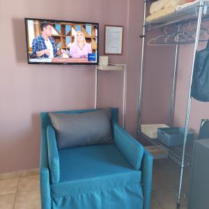 帕特雷的住宿－Urban Penthouse，墙上配有电视的房间的蓝色椅子