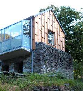 une maison au-dessus d'un mur en pierre dans l'établissement Maison 4 petite Casa design nel parco naturale, à Crodo
