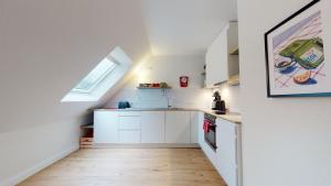 an attic kitchen with white cabinets and a window at Löningen - Ferienwohnung Hasestraße in Löningen
