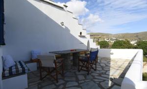 a patio with a table and chairs on a white wall at Lovely Studio Apartment For 2 Ppl In Tinos in Agios Sostis