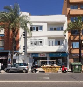 a building on a city street with palm trees and cars at UIM Mediterraneo ATICO Hispanidad 3 Wifi in Puerto de Sagunto